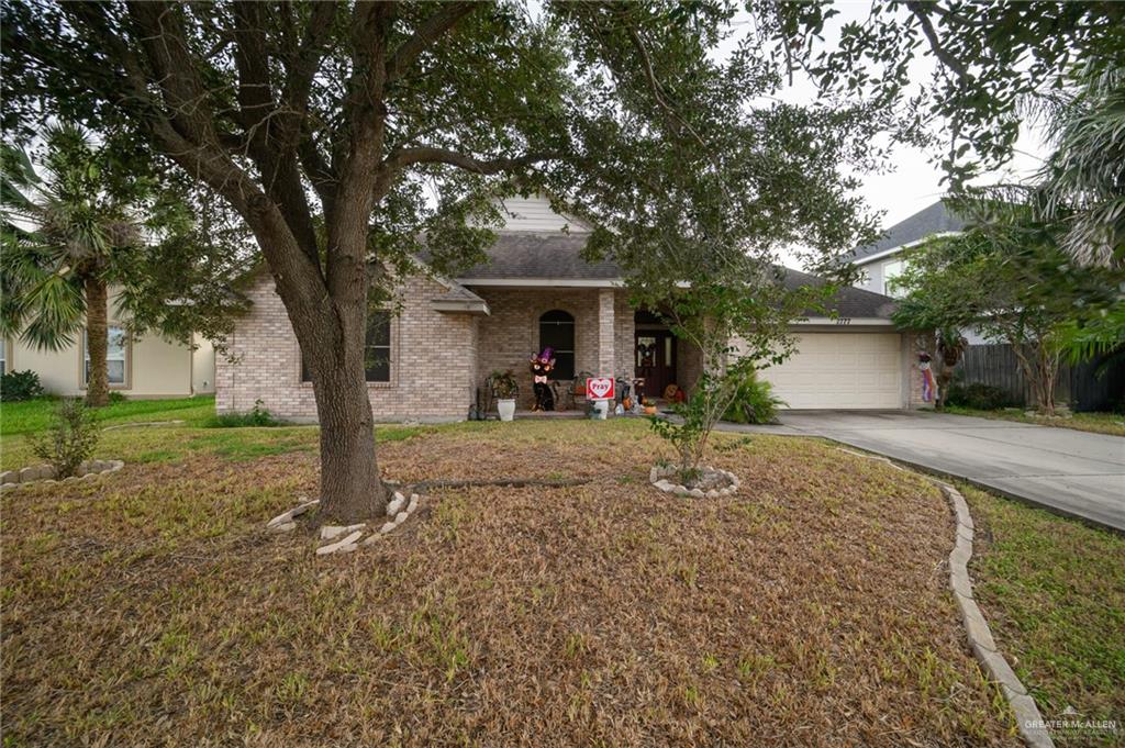 a view of a house with a yard and large tree