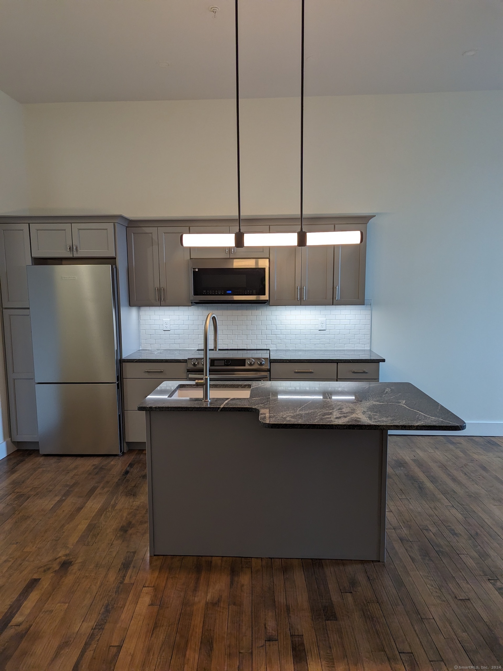 a kitchen with kitchen island stainless steel appliances a sink and wooden floor