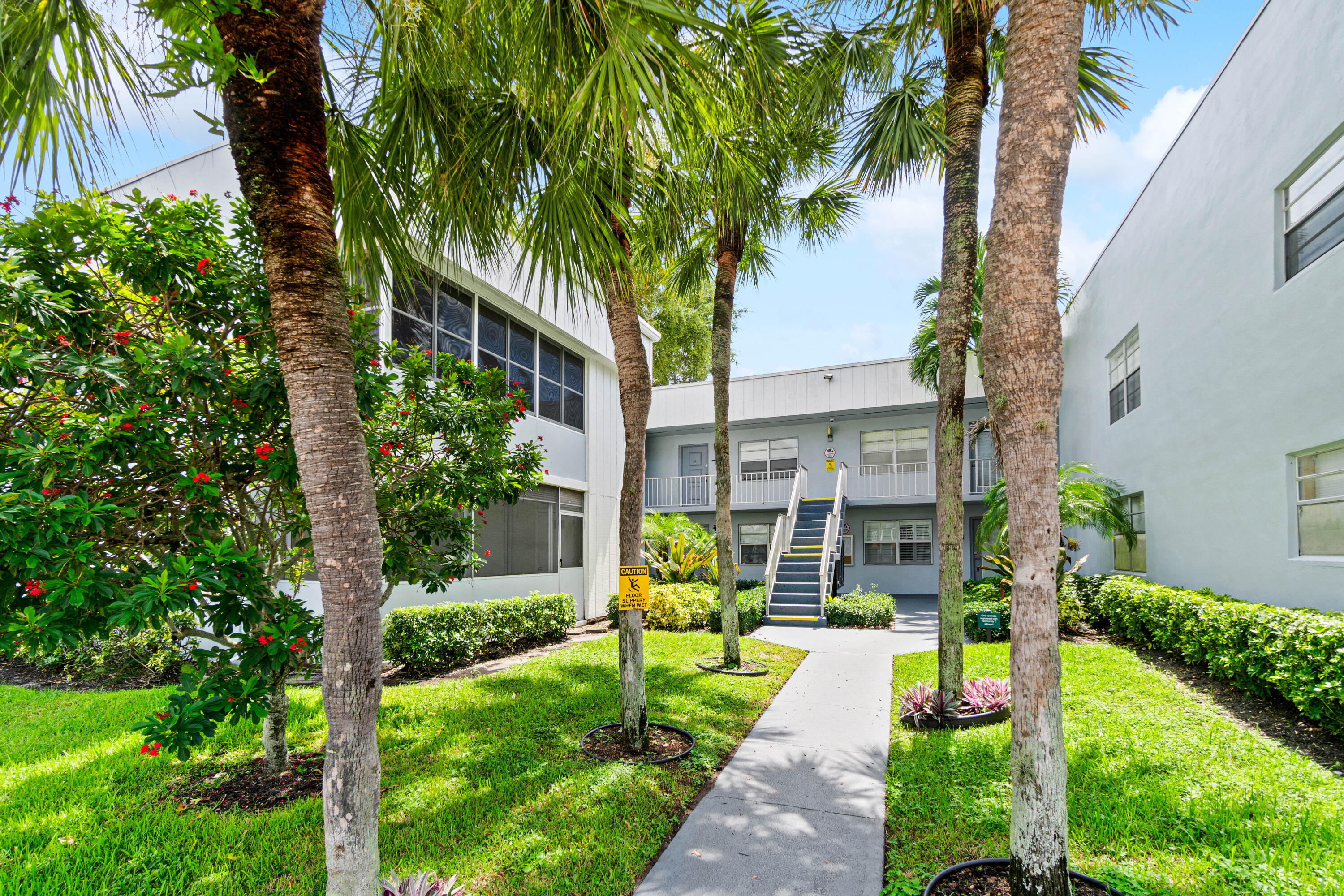 a view of yellow house with a big yard plants and large trees