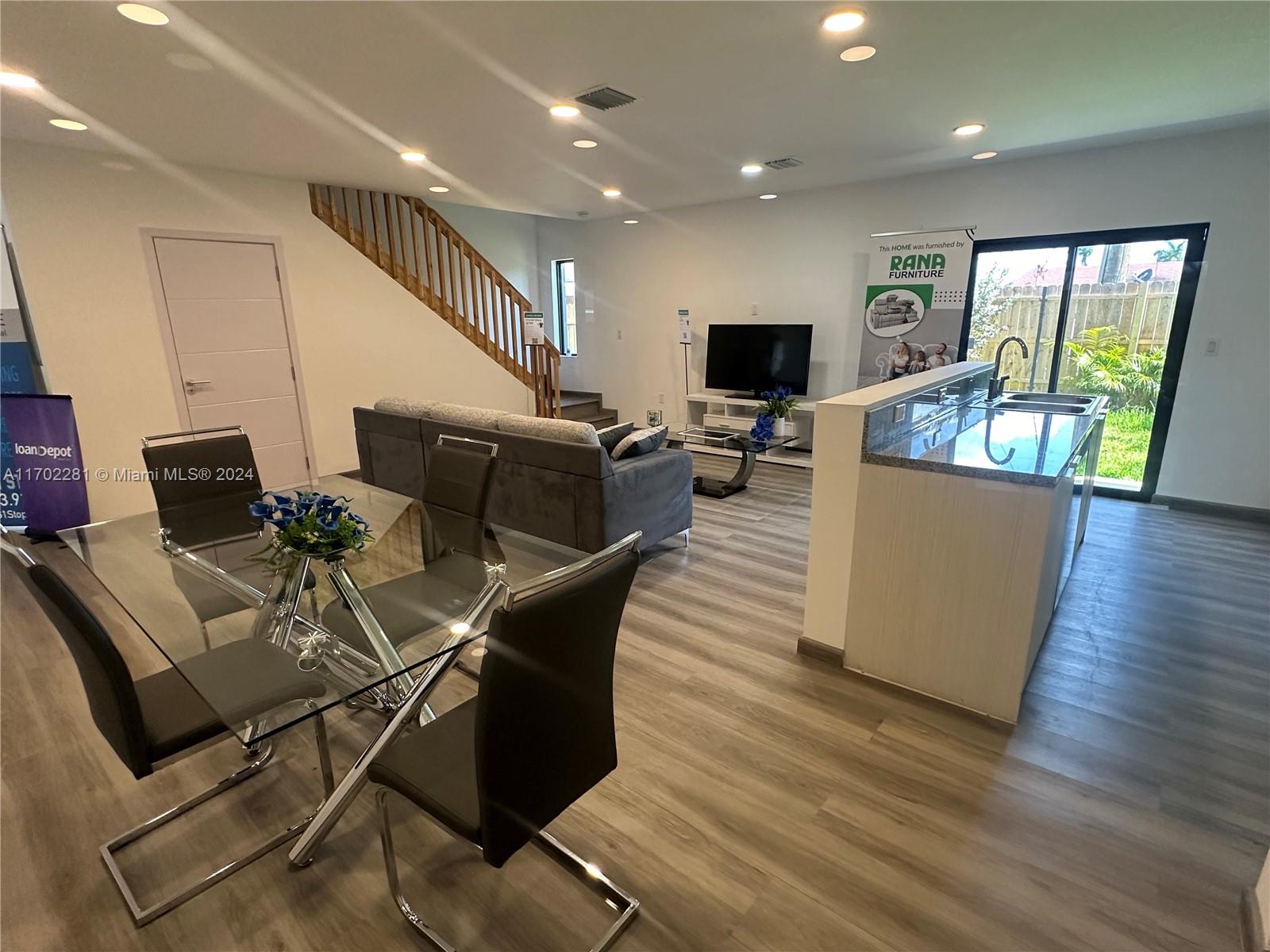 a living room with furniture a flat screen tv and wooden floor