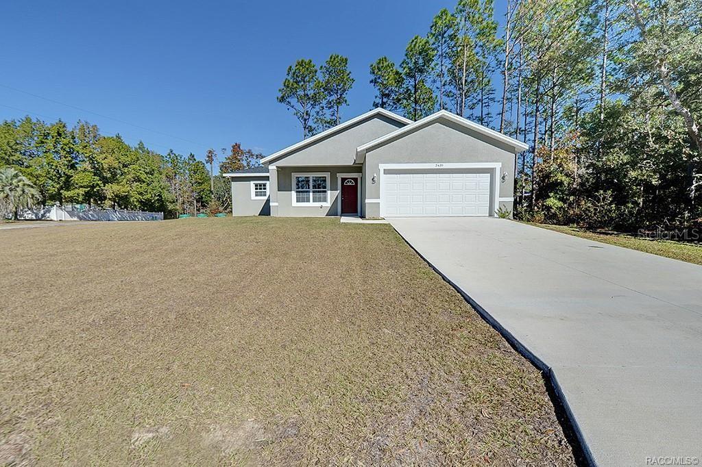 front view of house with a yard and trees all around