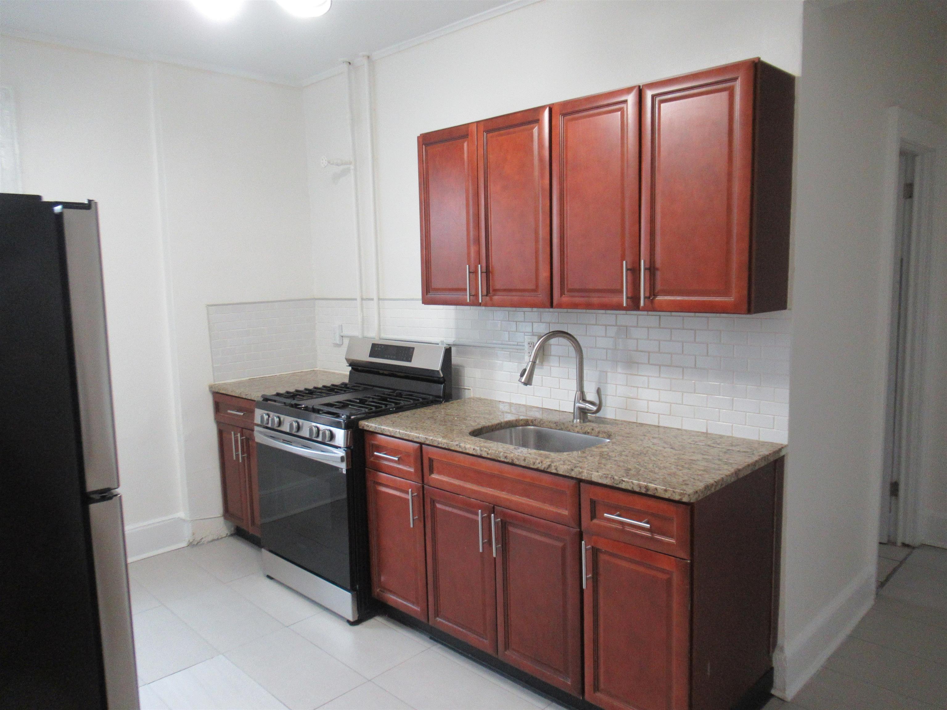 a kitchen with granite countertop a sink stove and refrigerator