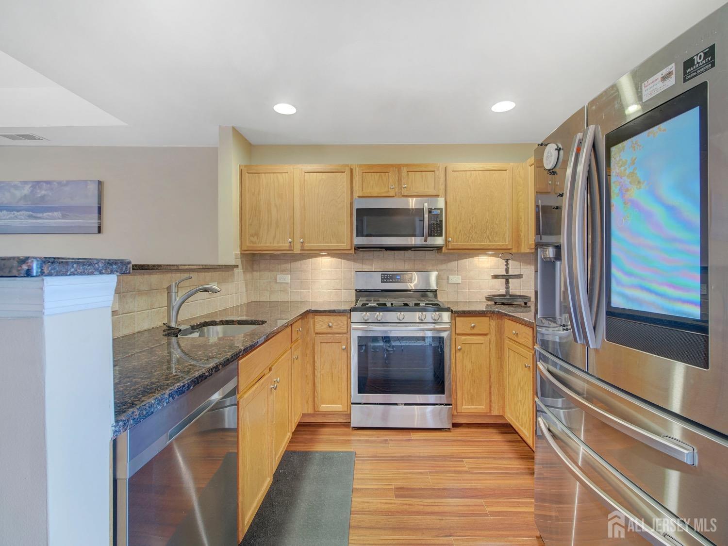 a kitchen with stainless steel appliances granite countertop a sink stove microwave and refrigerator