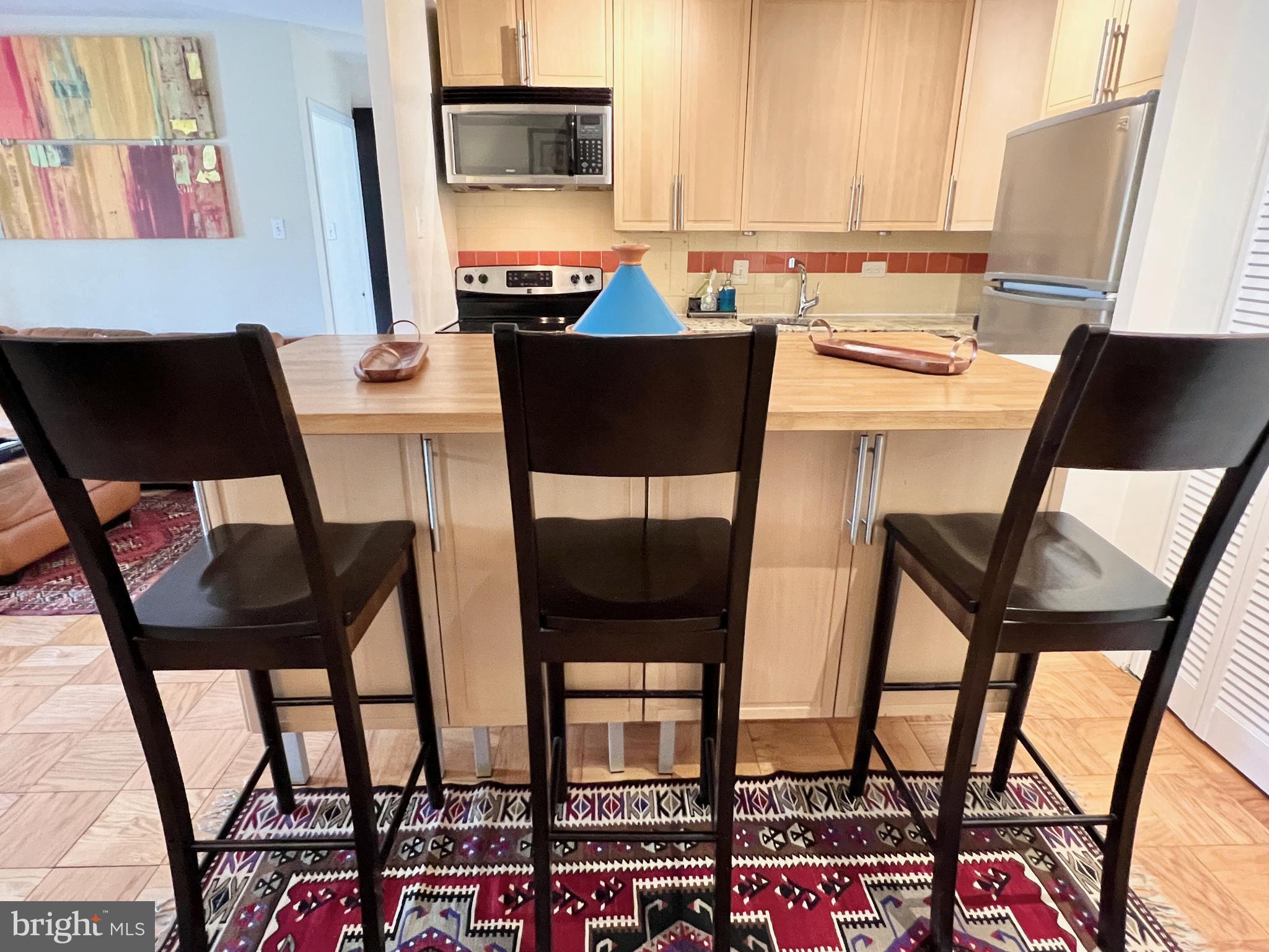 a kitchen with stainless steel appliances a table chairs and a refrigerator