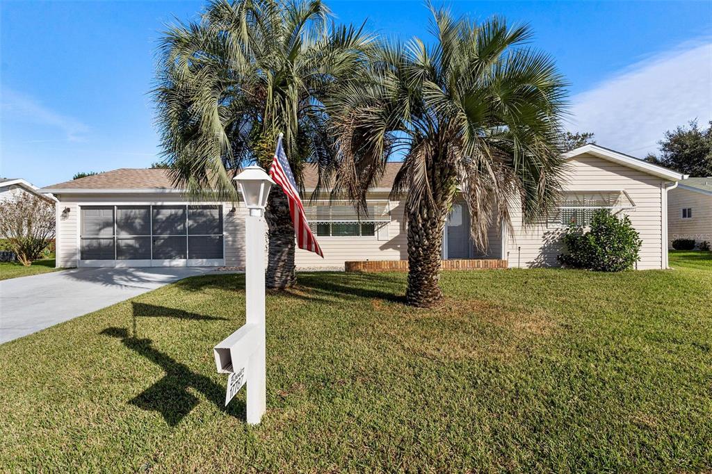 front view of house with a yard and palm trees