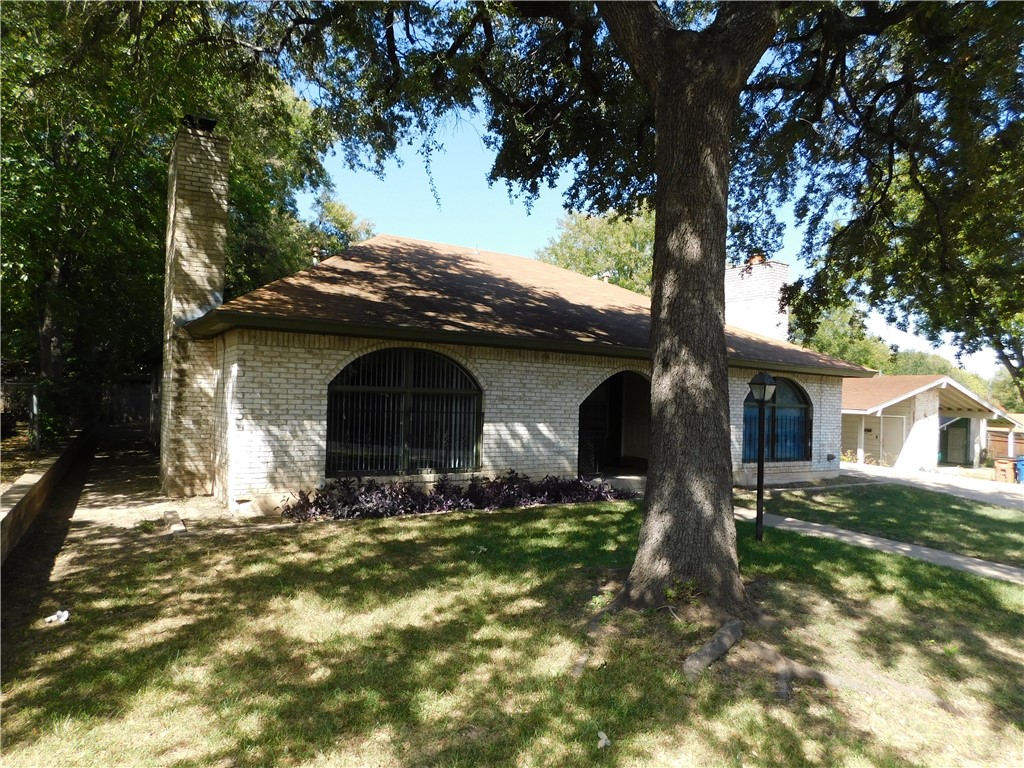 a view of house with yard and trees in the background