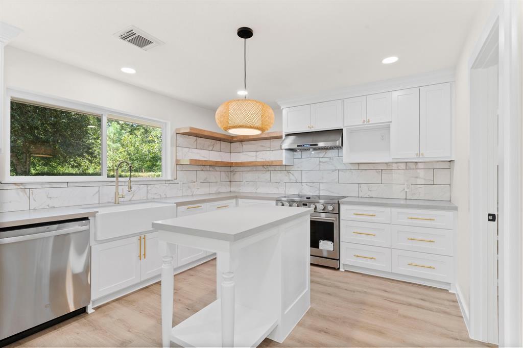 a kitchen with a stove a sink a window and cabinets