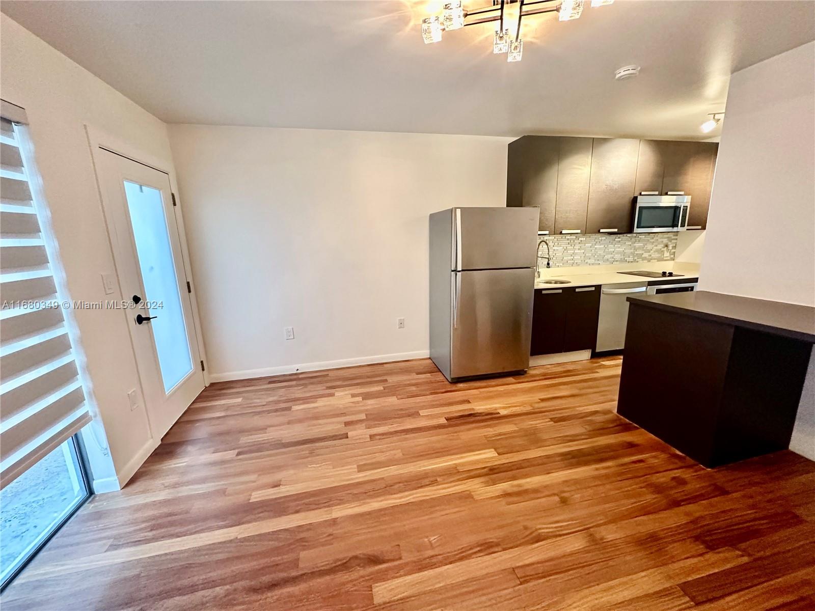 a view of a kitchen with wooden floor and electronic appliances