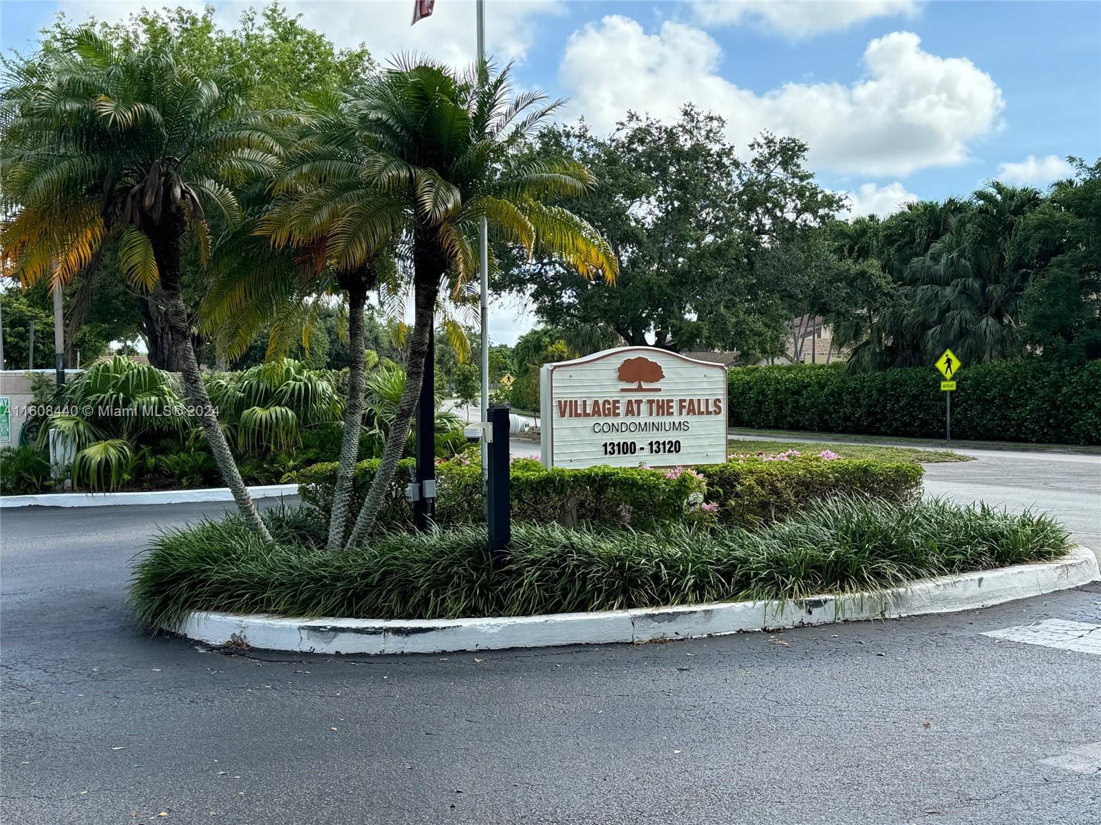 a view of a park that has a sign board plants and trees