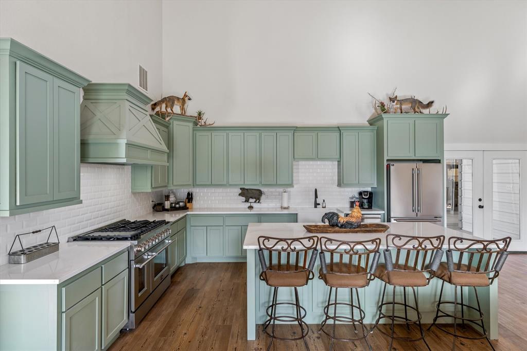 Kitchen featuring premium appliances, green cabinetry, dark wood-type flooring, and custom exhaust hood