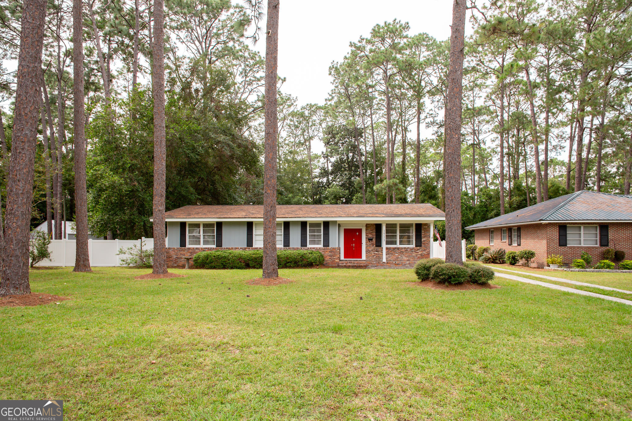 a front view of a house with garden and trees