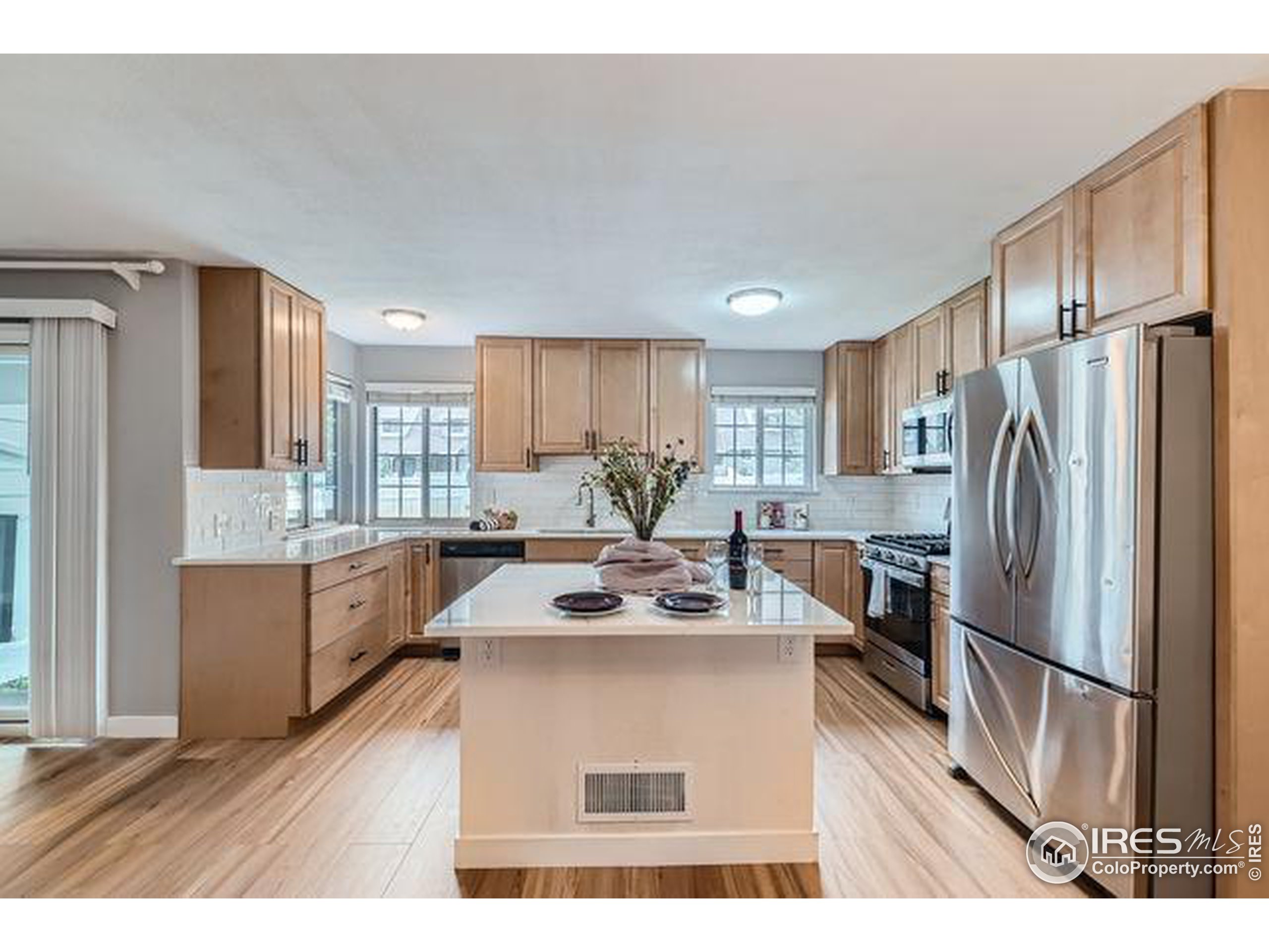 a kitchen with stainless steel appliances granite countertop a refrigerator sink and white cabinets