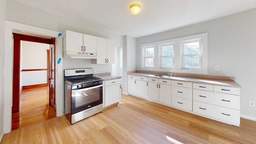 a kitchen with granite countertop a stove a sink and a refrigerator