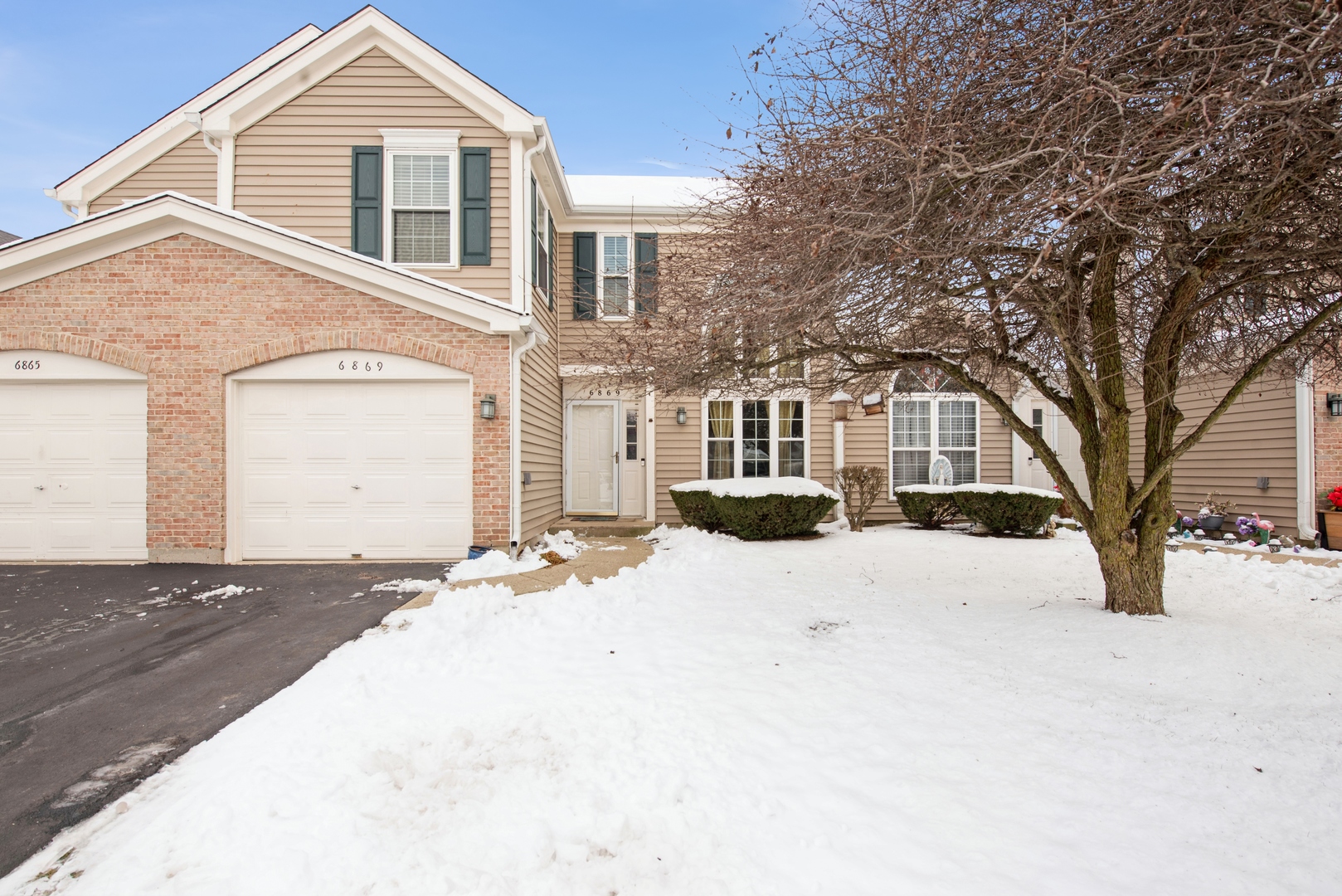 a front view of a house with a yard covered in snow