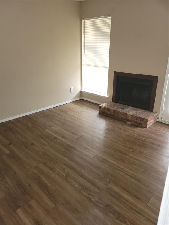 a view of empty room with wooden floor and fireplace