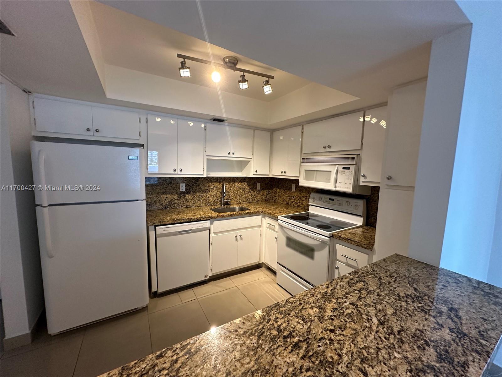 a kitchen with a sink a stove a refrigerator and white cabinets