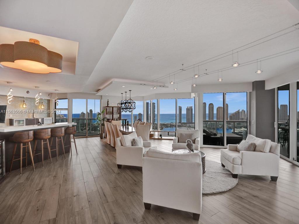 a living room with couches a coffee table and kitchen view with wooden floor