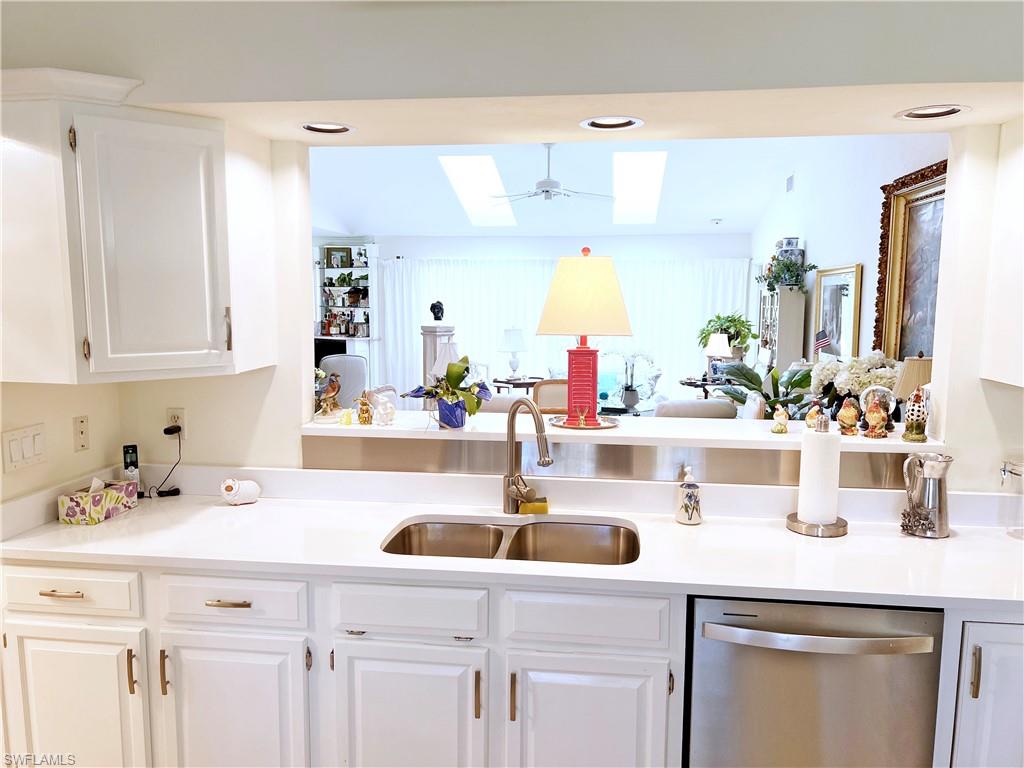 a kitchen with white cabinets a sink and dishwasher with wooden floor