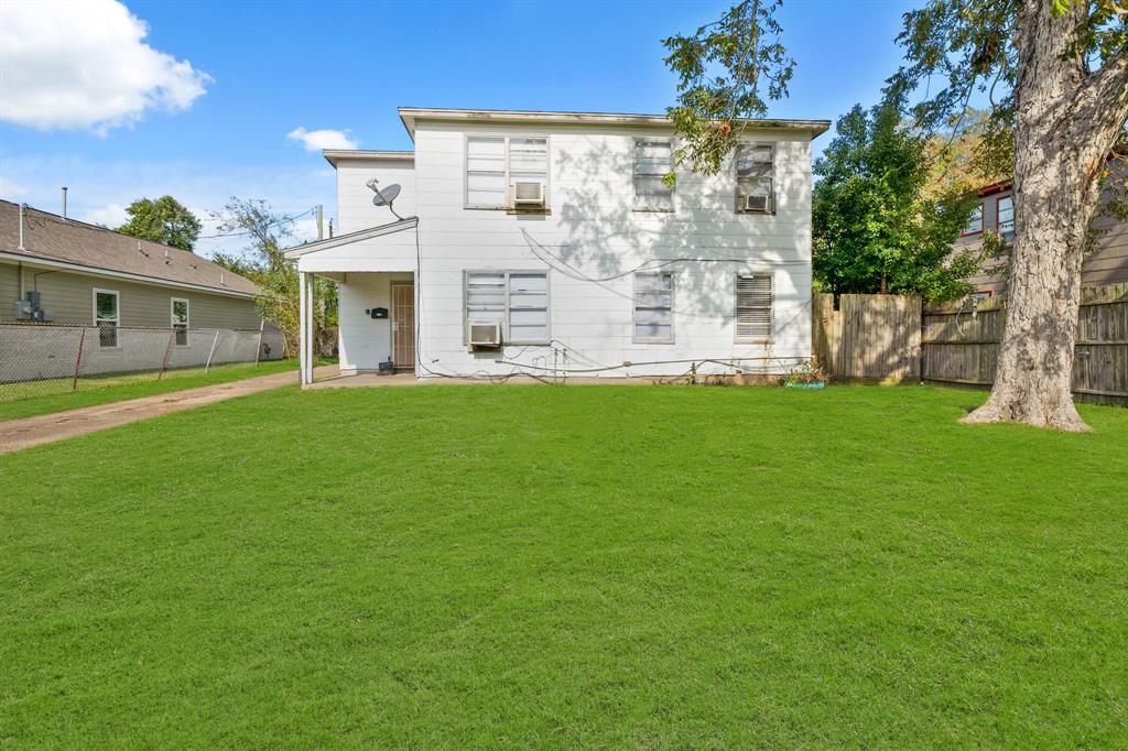 a view of a white house next to a yard with big trees