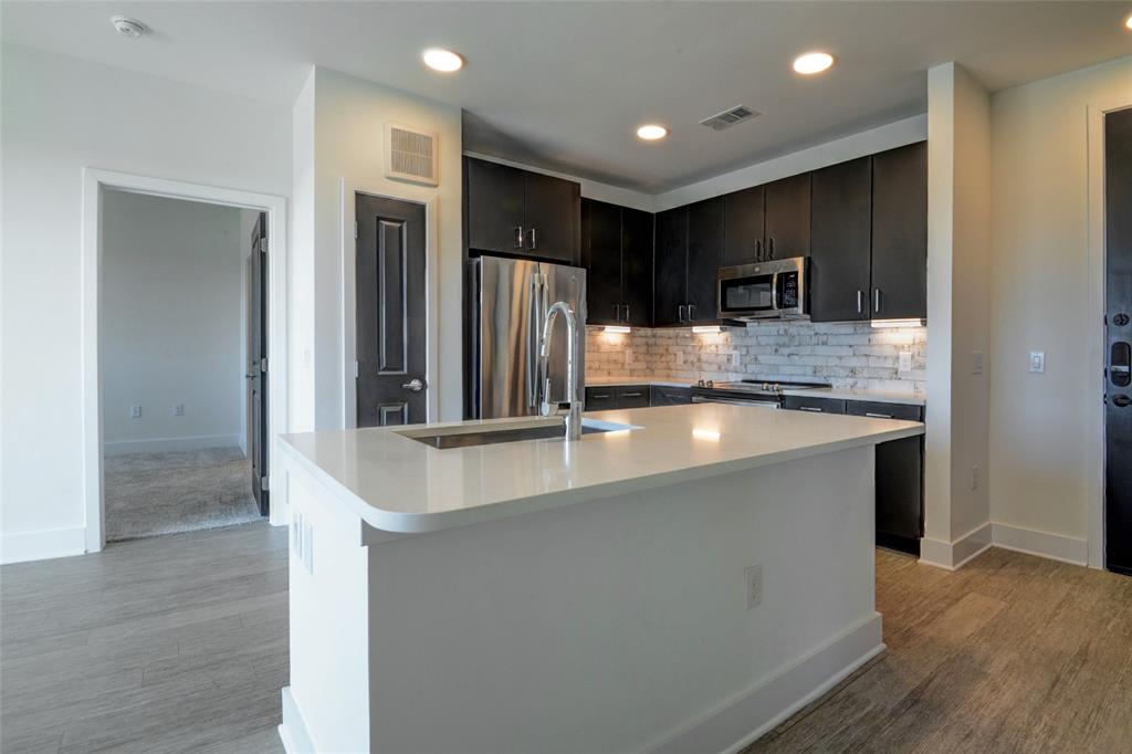 a large kitchen with stainless steel appliances a large counter top and a refrigerator