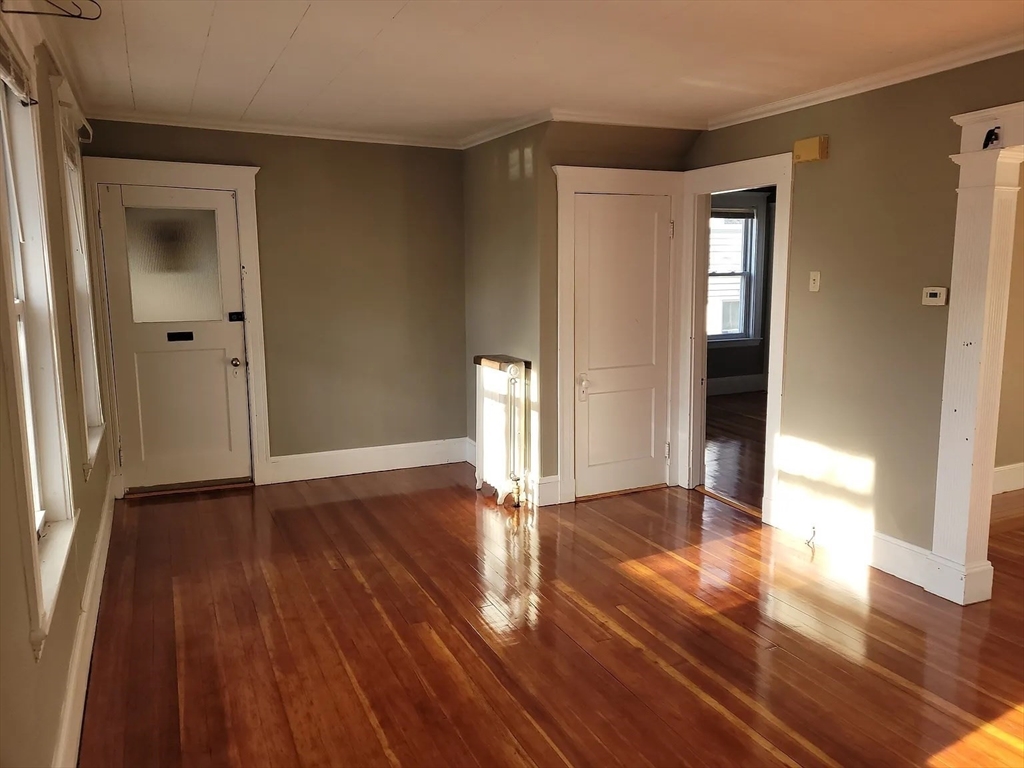 a view of empty room with wooden floor and window