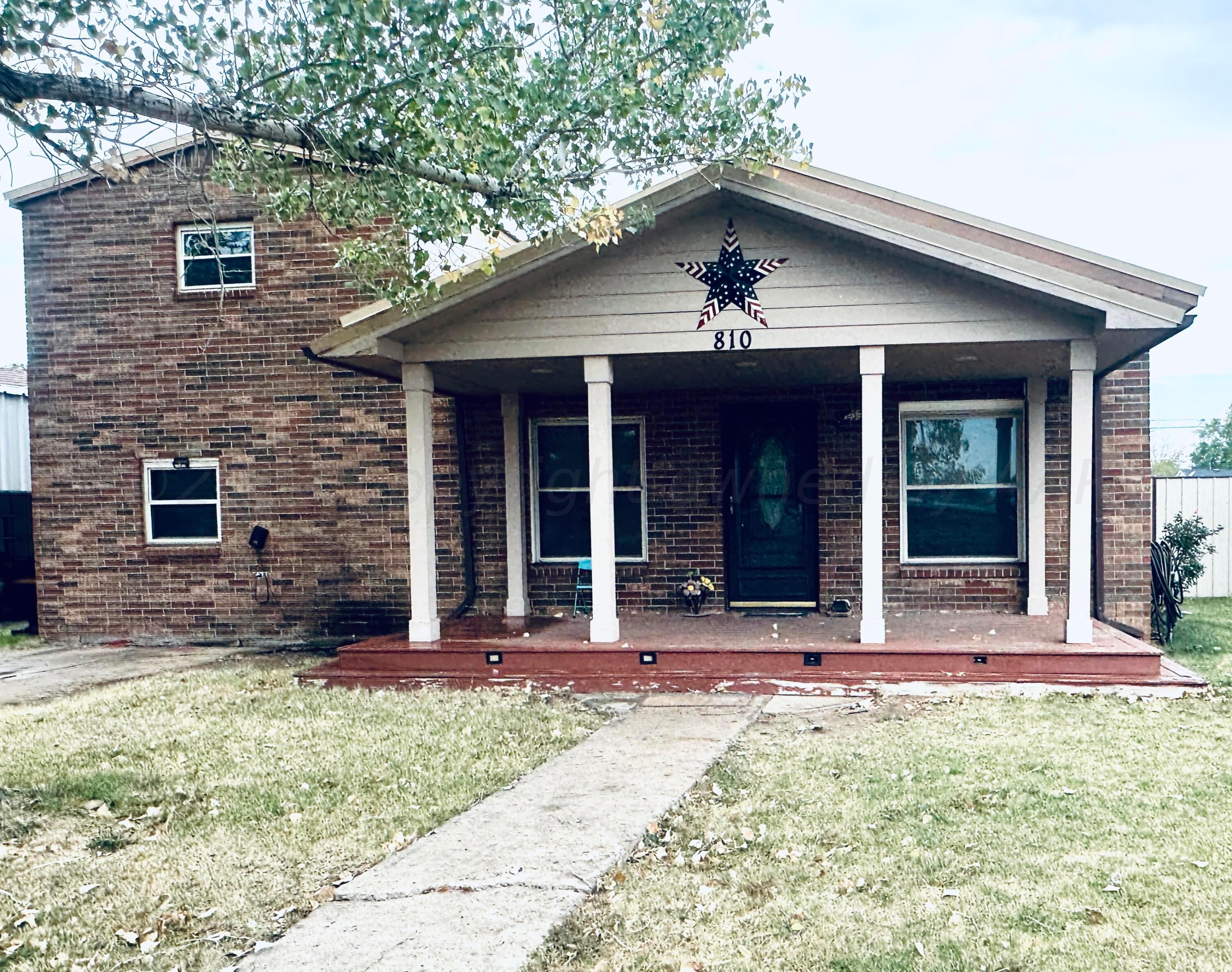 front view of a brick house with a yard