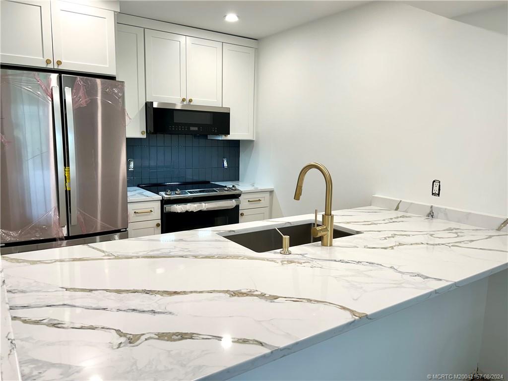 a kitchen with granite countertop a refrigerator and a sink