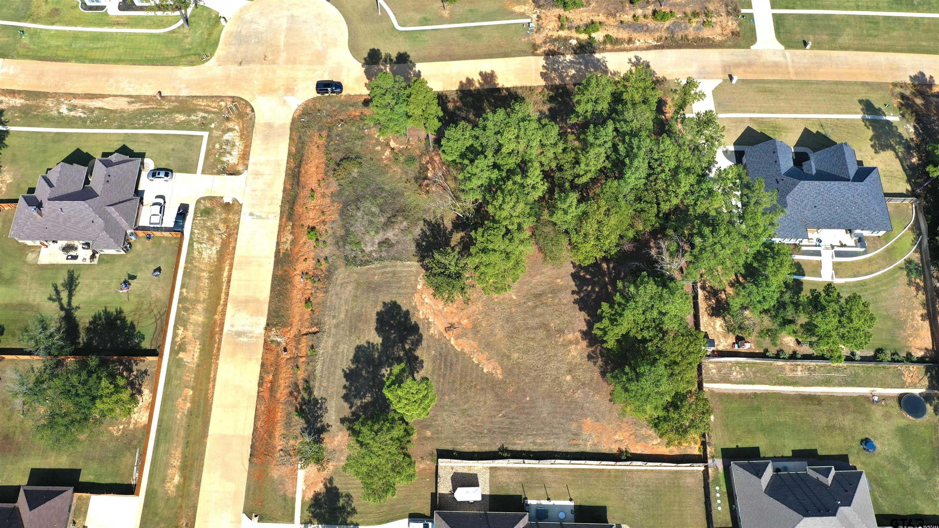 an aerial view of residential houses with outdoor space and trees