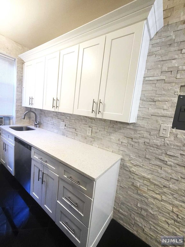 a utility room with granite countertop cabinets sink and a window