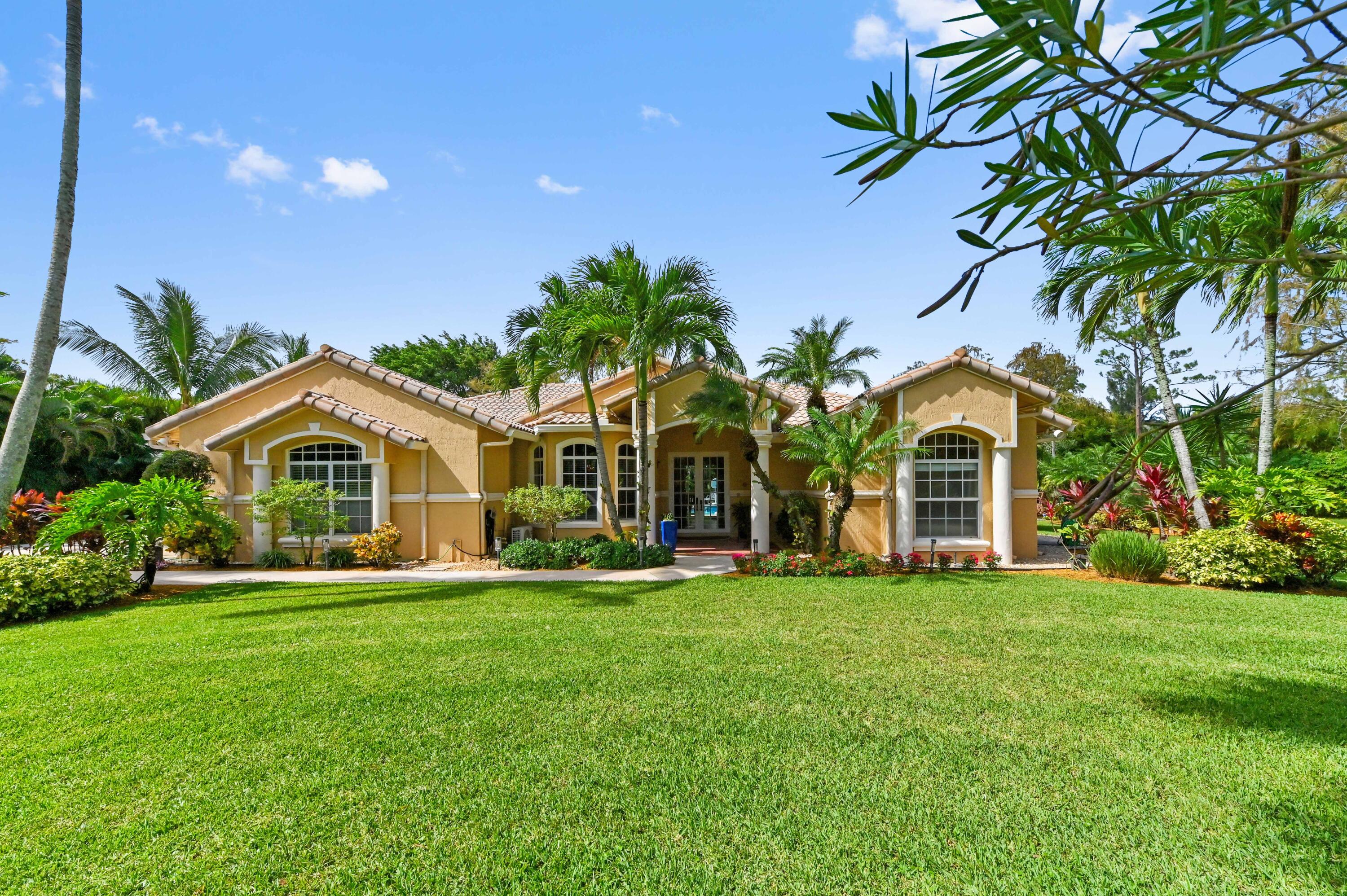 a front view of a house with a garden and trees