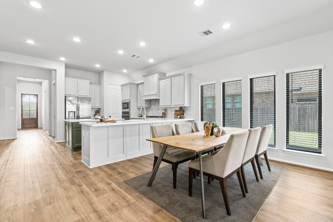 a kitchen with a dining table chairs and wooden floor