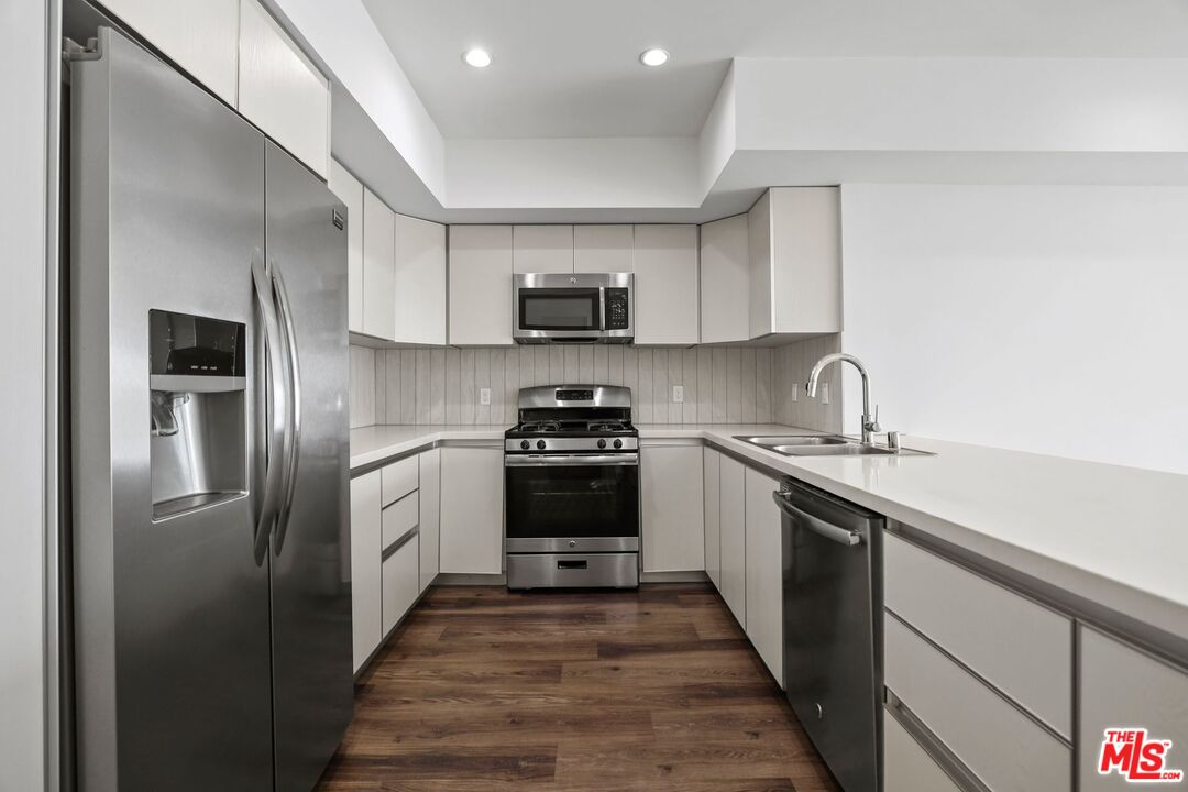 a kitchen with stainless steel appliances granite countertop a refrigerator and a stove