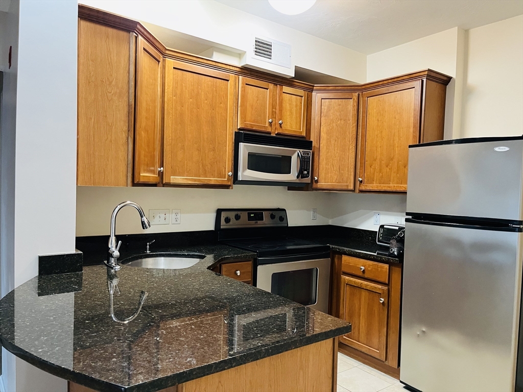 a kitchen with granite countertop a refrigerator a stove and a sink