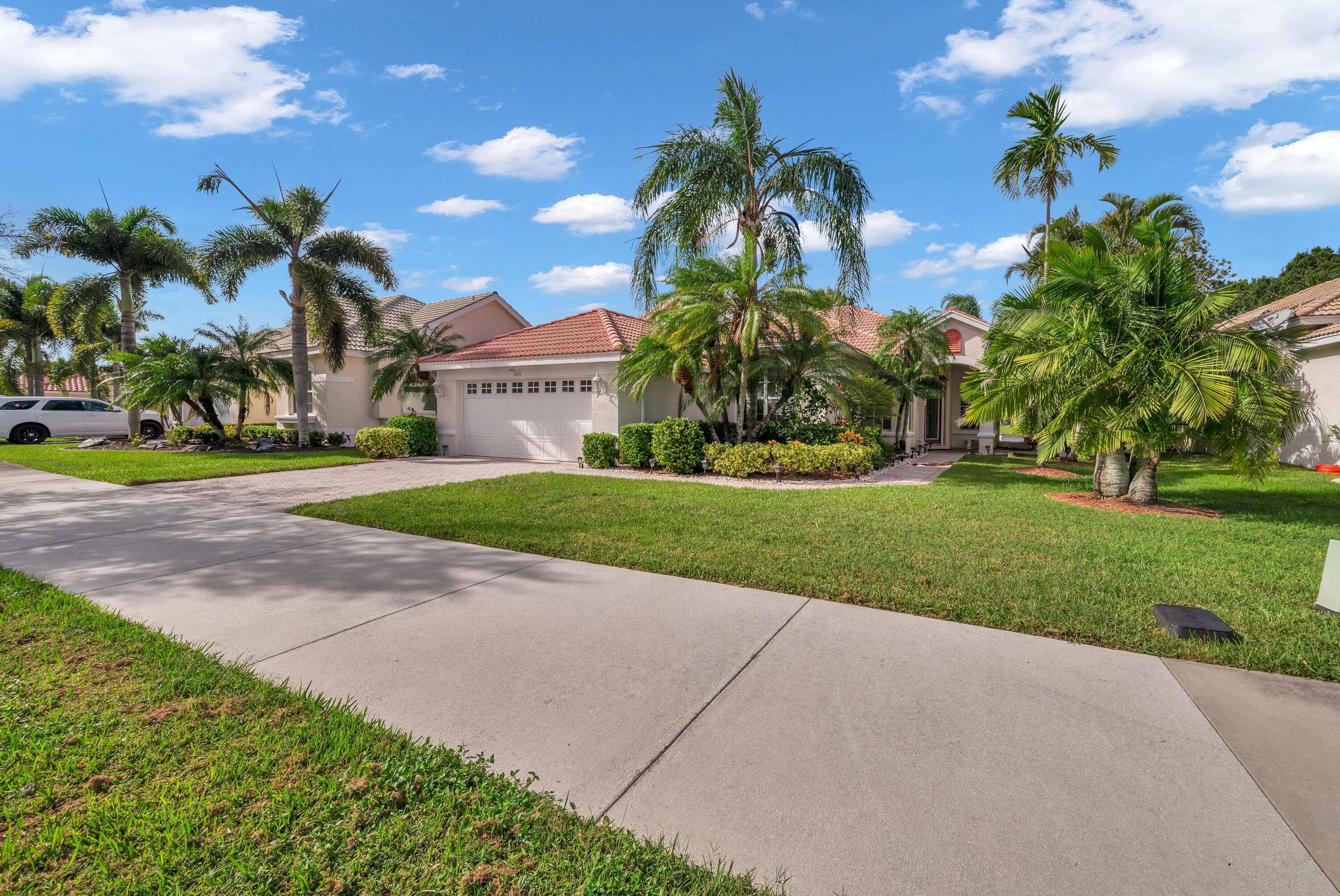 a view of a house with a yard and palm trees