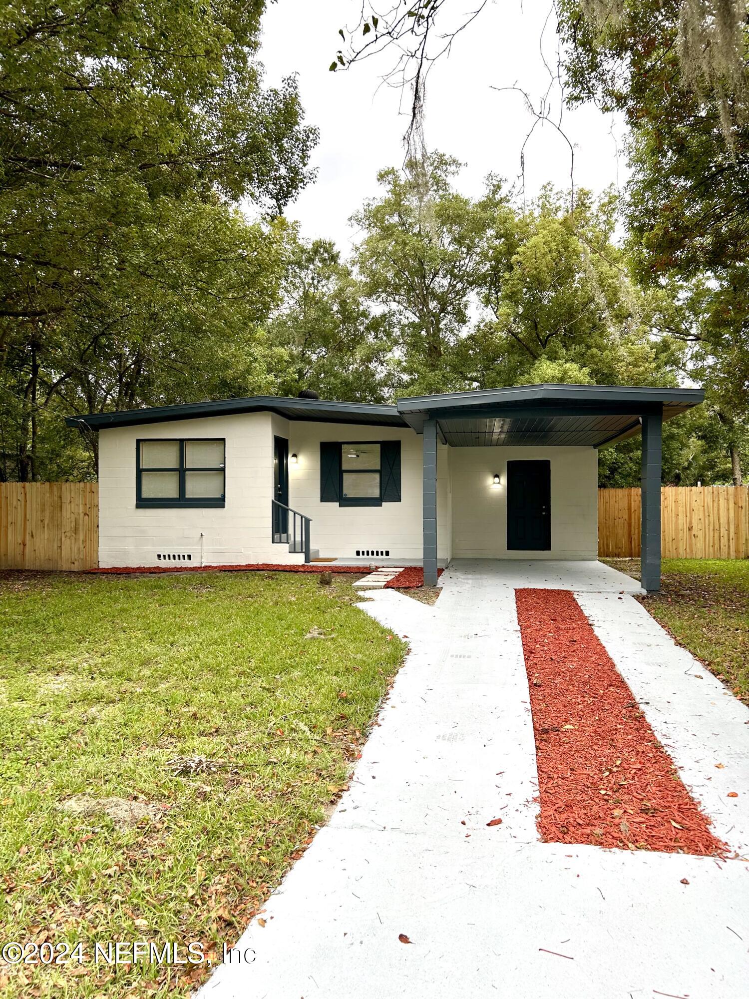 a front view of house with yard and trees in the background