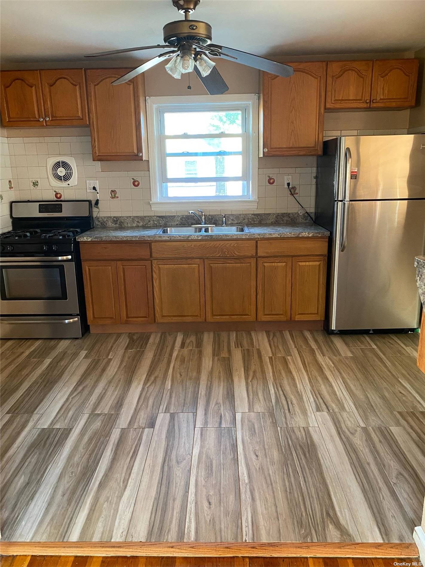 a kitchen with granite countertop a sink cabinets stainless steel appliances and a window