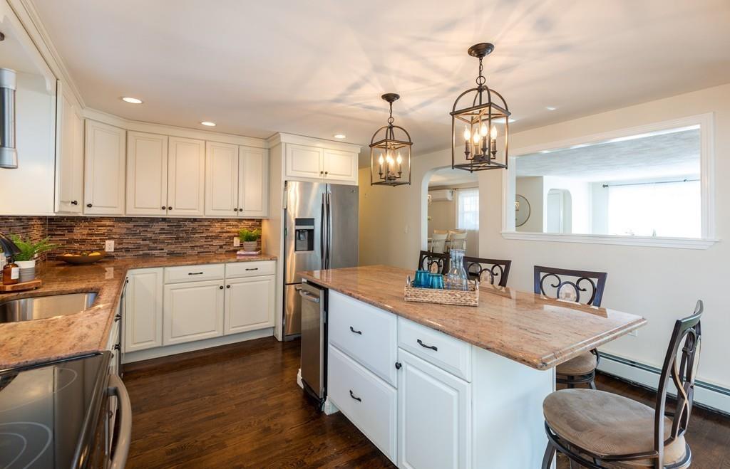 a kitchen with kitchen island granite countertop a sink cabinets and wooden floor