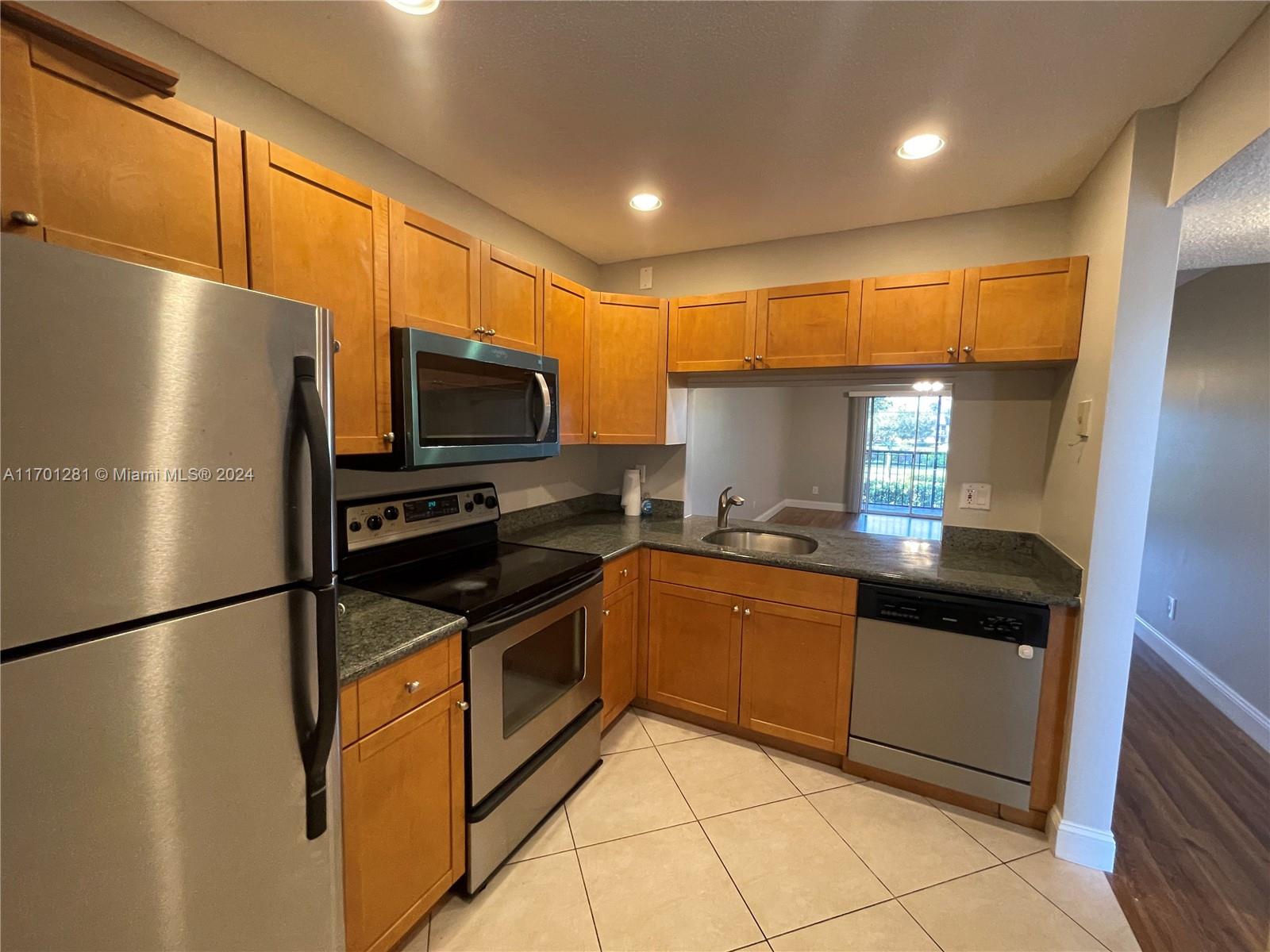 a kitchen with stainless steel appliances granite countertop a refrigerator a sink and a stove