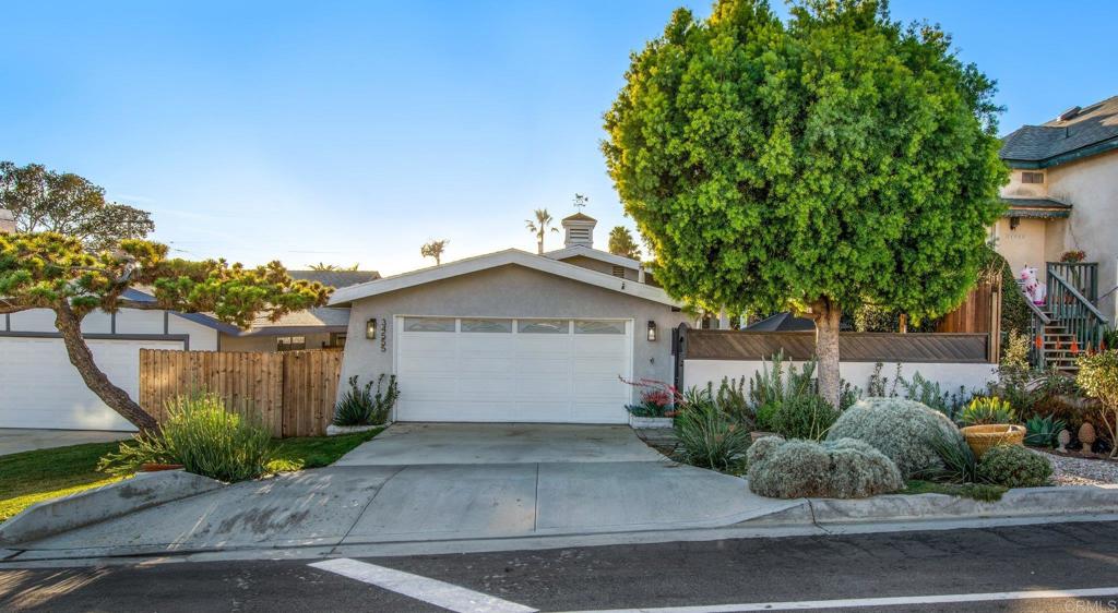 a view of a house with a yard plants and large tree