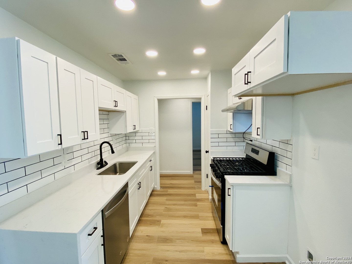 a kitchen with stainless steel appliances a sink stove and cabinets