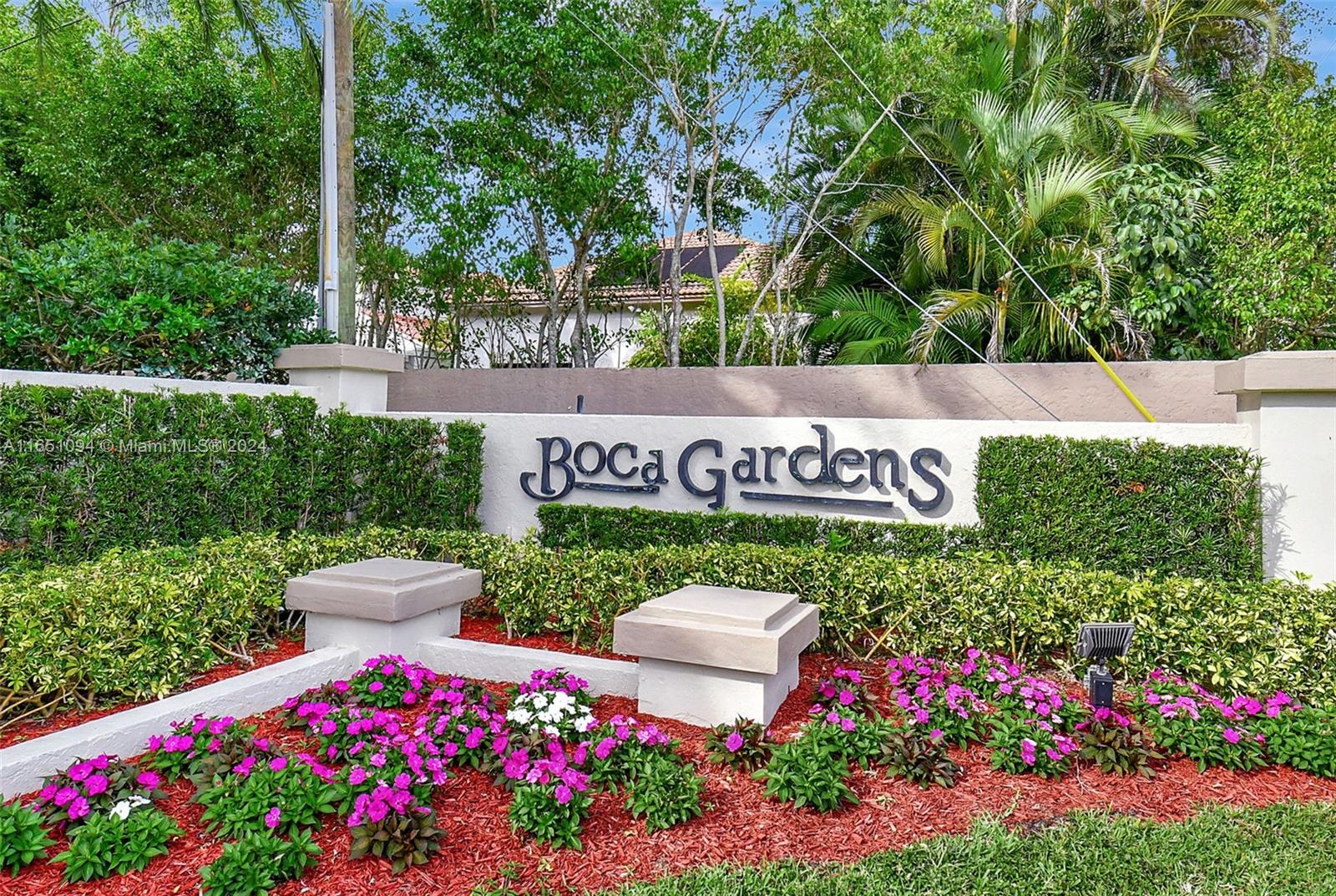 a view of sign board with yard and flowers