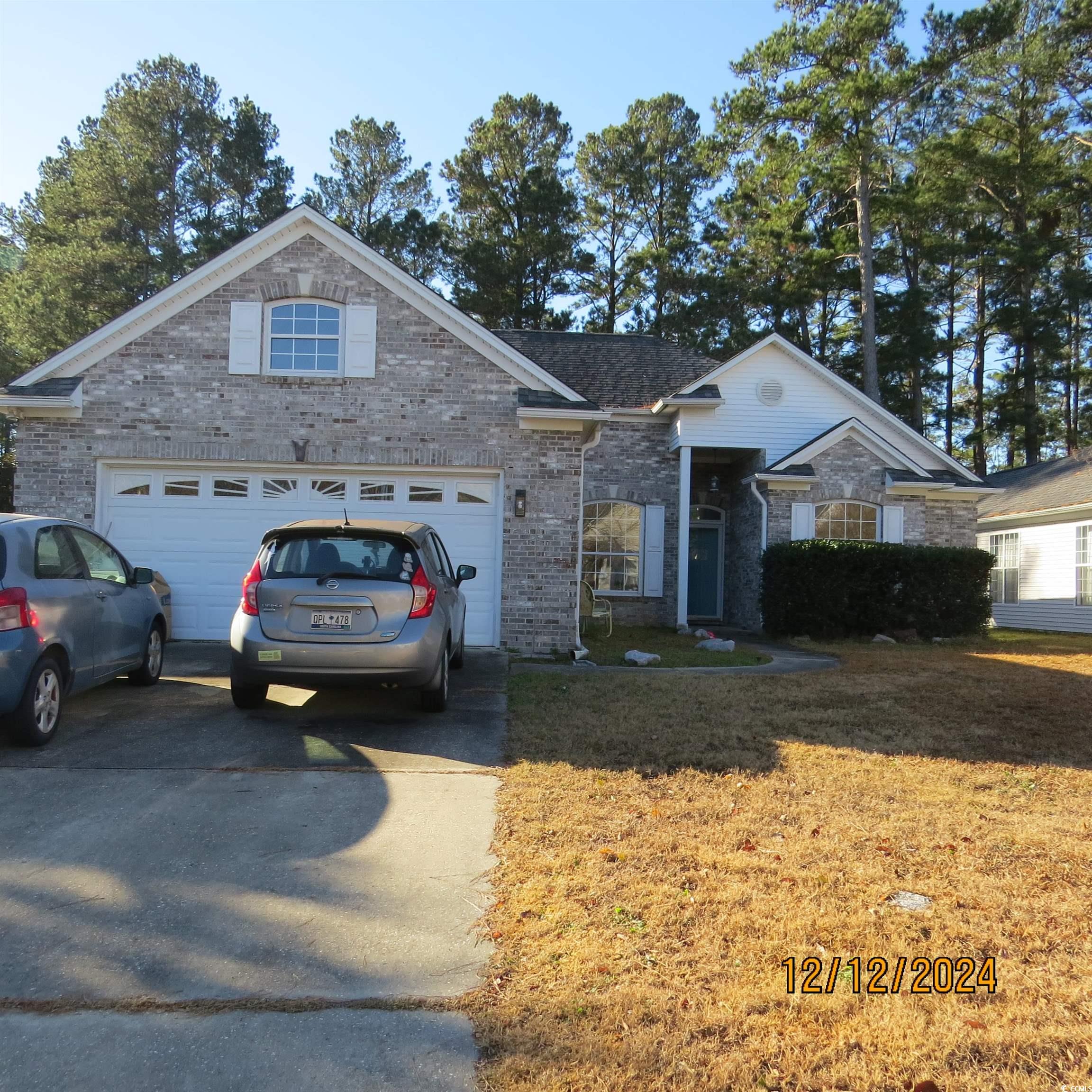 Ranch-style home featuring a front yard and a gara