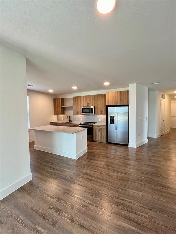 a large kitchen with kitchen island a refrigerator and a stove