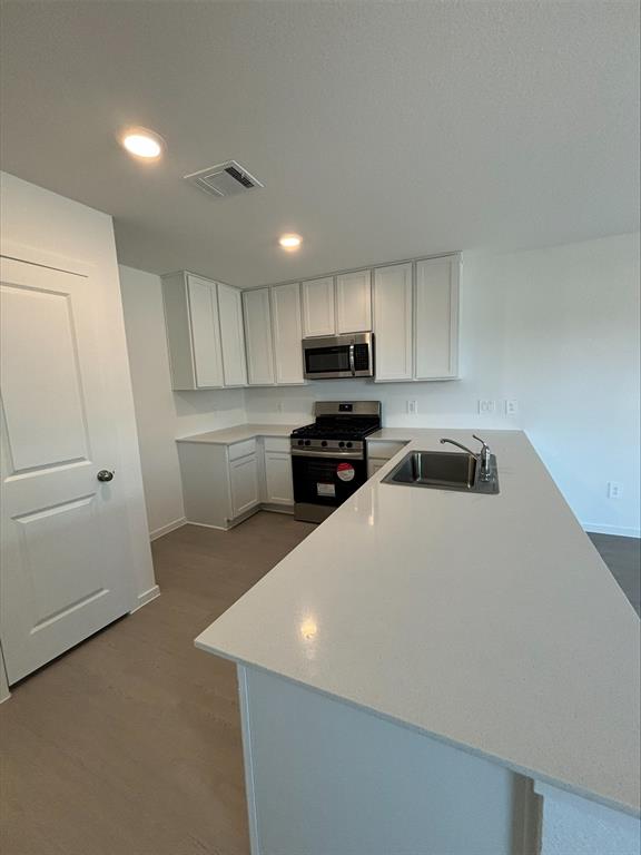 a kitchen with granite countertop a refrigerator sink and white cabinets