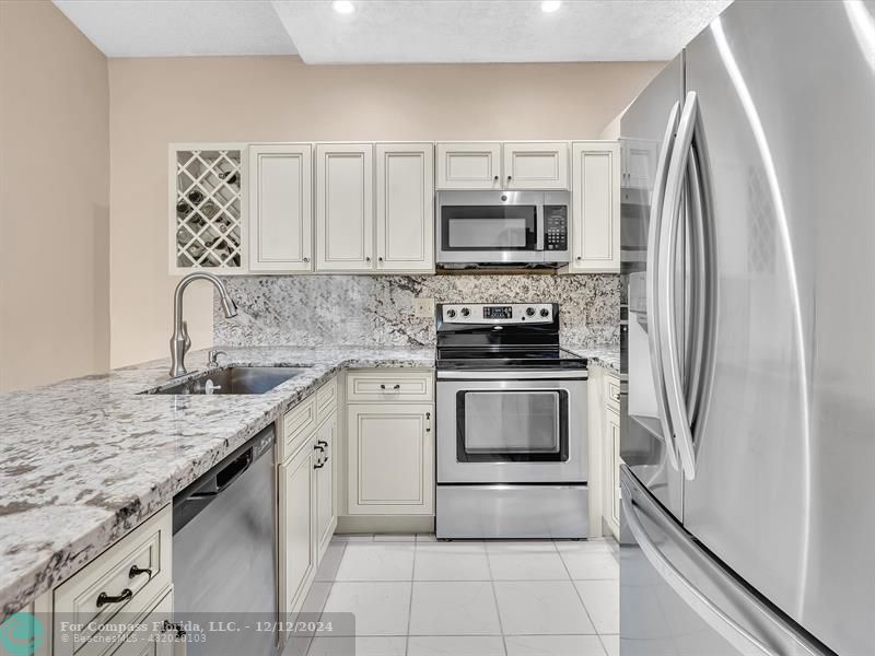 a kitchen with stainless steel appliances granite countertop a refrigerator sink and stove