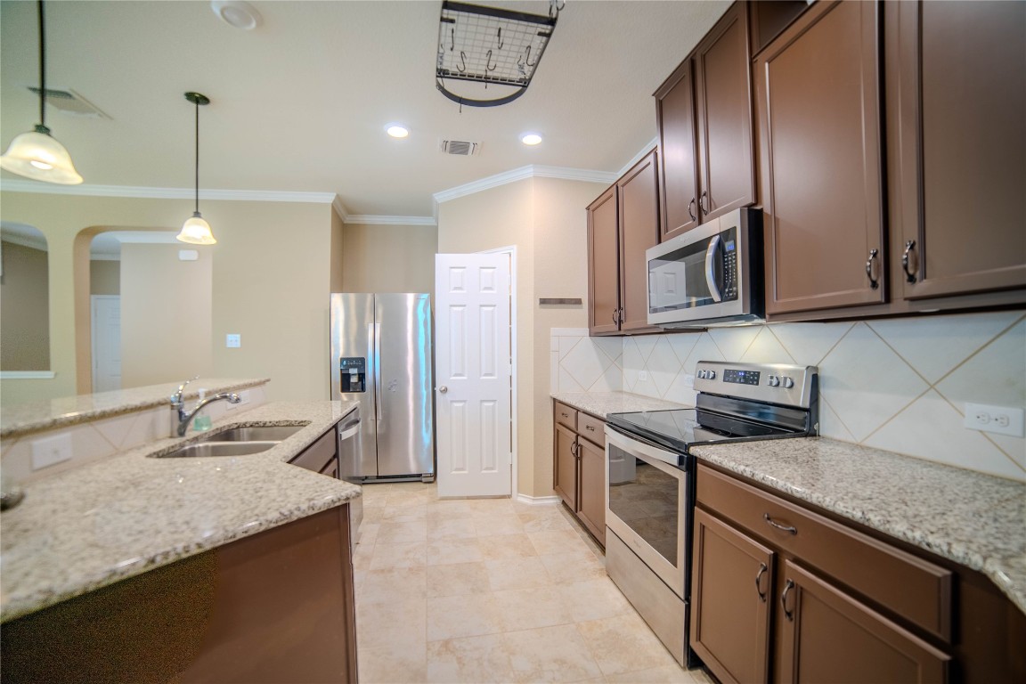 a kitchen with stainless steel appliances granite countertop a sink a stove and a refrigerator