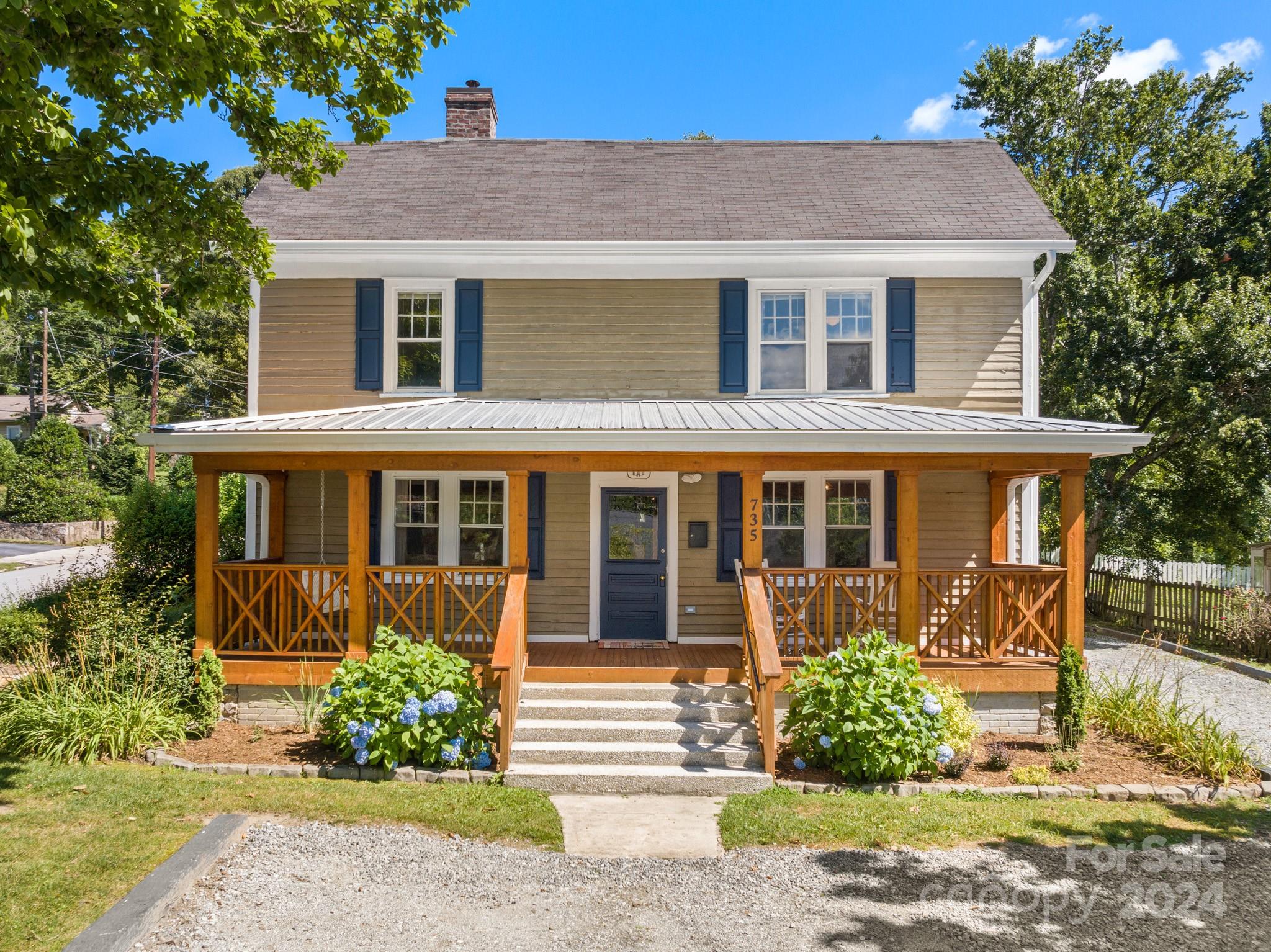 a front view of a house with a yard and potted plants