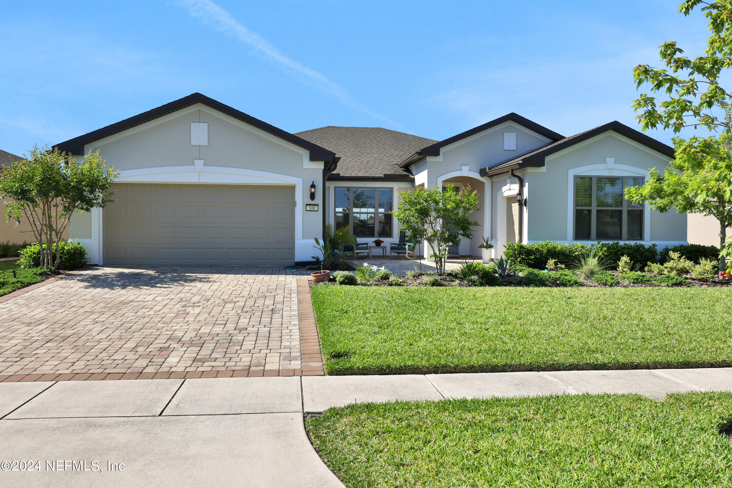 a front view of a house with a yard and potted plants