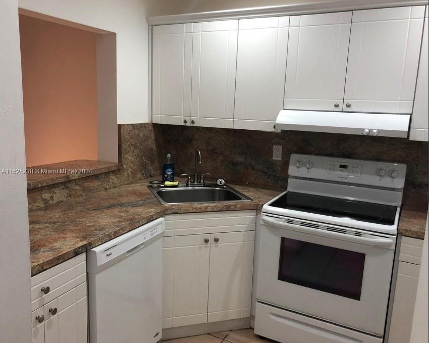 a kitchen with granite countertop white cabinets and white appliances