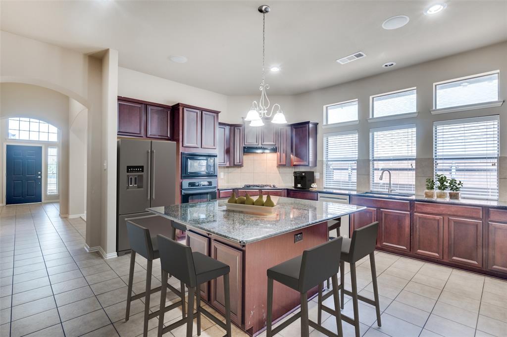 a kitchen with stainless steel appliances granite countertop a table chairs sink refrigerator and granite counter top